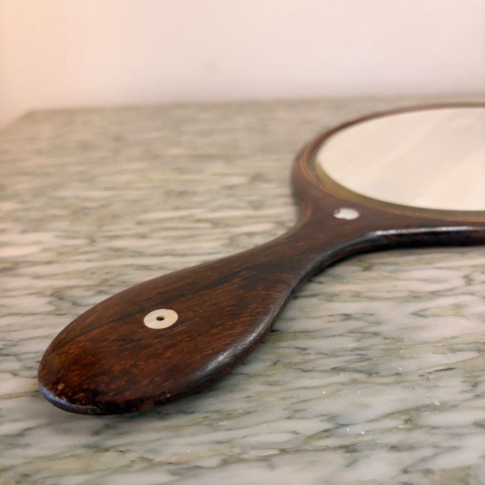 An oval antique rosewood hand mirror featuring mother-of-pearl inlay on the contoured handle and a bevelled glass plate. View III