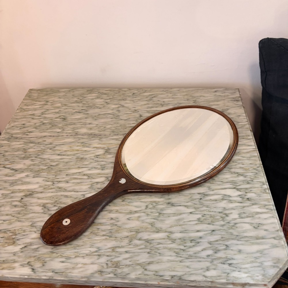 An oval antique rosewood hand mirror featuring mother-of-pearl inlay on the contoured handle and a bevelled glass plate. View IV