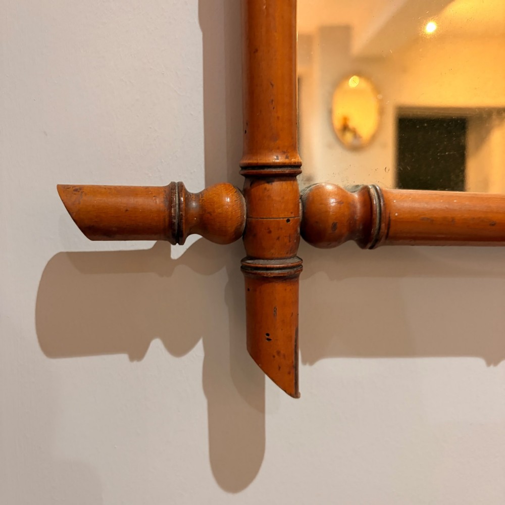 A square wall mirror framed in warm brown turned wood carved to resemble bamboo with extended corner joints and a metal suspension chain. View II