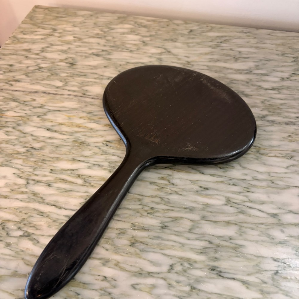 A Victorian oval ebony hand mirror featuring a bevelled glass mirror plate and a carved tapered handle. View III