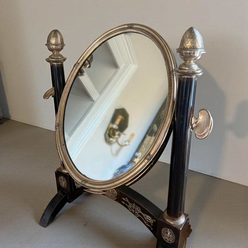 An antique 19th-century French ebonised toilet mirror featuring an oval glass frame suspended between twin columns with silvered finials and an arched base. View III