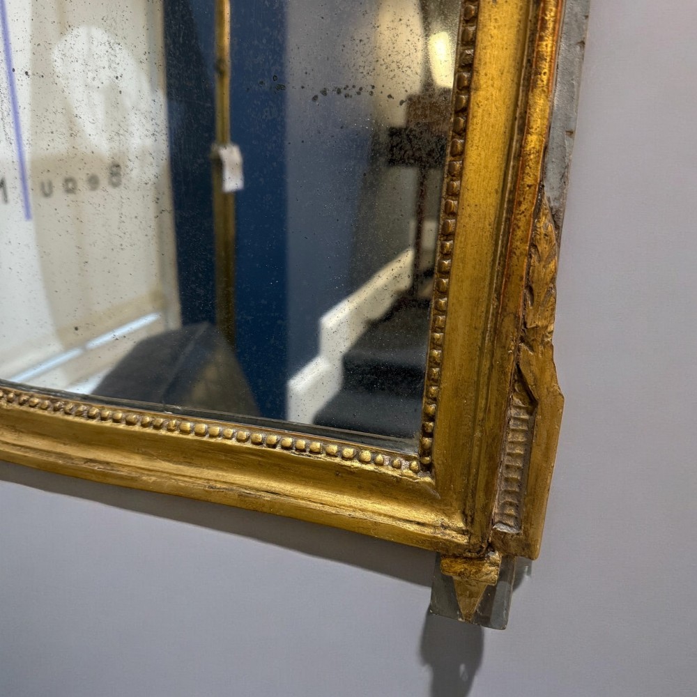 An early nineteenth-century rectangular giltwood wall mirror featuring an intricate carved cresting with a musical instrument motif and a beaded inner border. View III