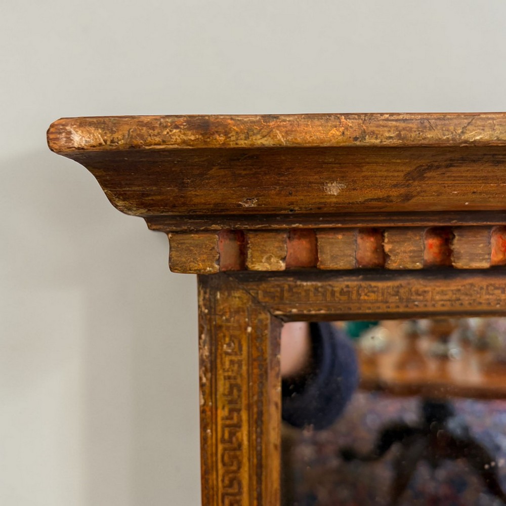 A nineteenth-century Neoclassical rectangular wall mirror featuring an architectural cornice, dentil moulding, carved Greek key border details, and foxed glass. View III