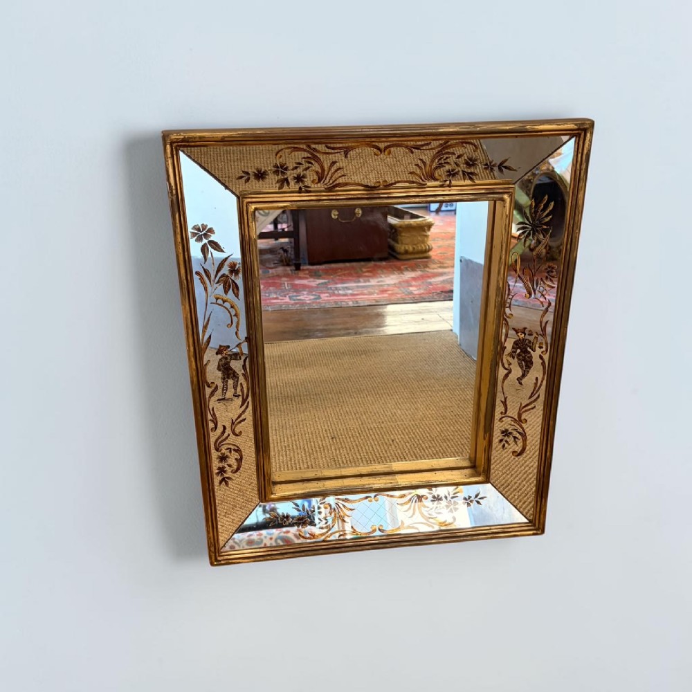 A rectangular wall mirror featuring a slender gilt frame surrounding a secondary reverse-painted eglomise border depicting Chinoiserie figures and floral motifs.