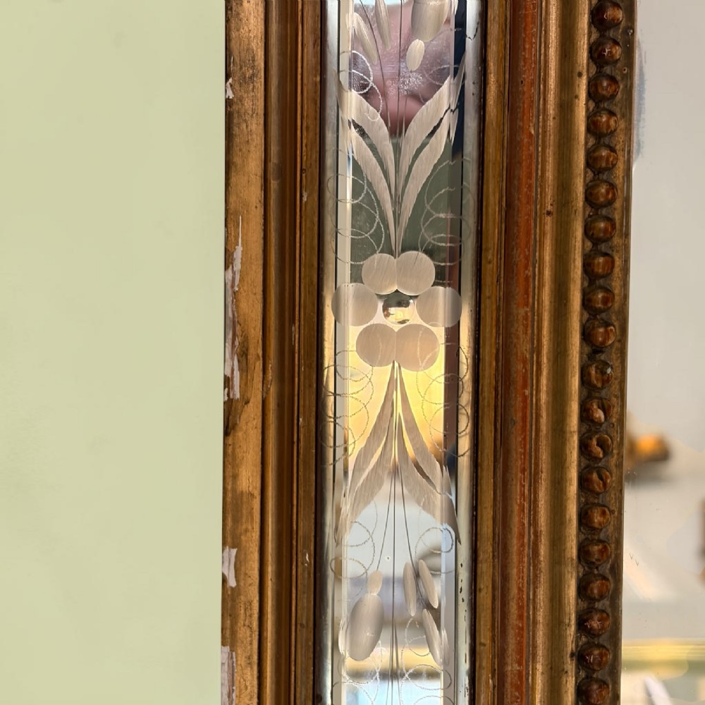 A rectangular French giltwood wall mirror featuring an ornate carved cresting, floral etched glass border panels, and a central mirror plate. View II