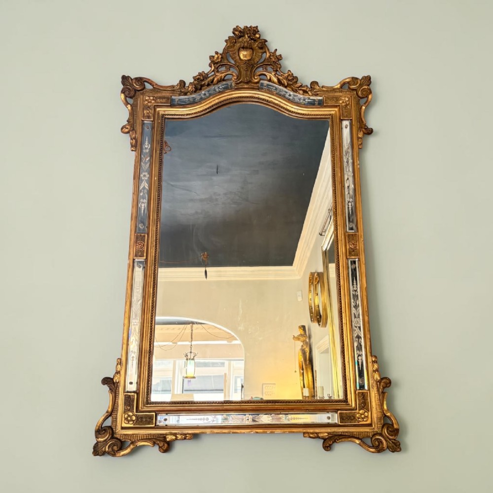 A rectangular French giltwood wall mirror featuring an ornate carved cresting, floral etched glass border panels, and a central mirror plate.