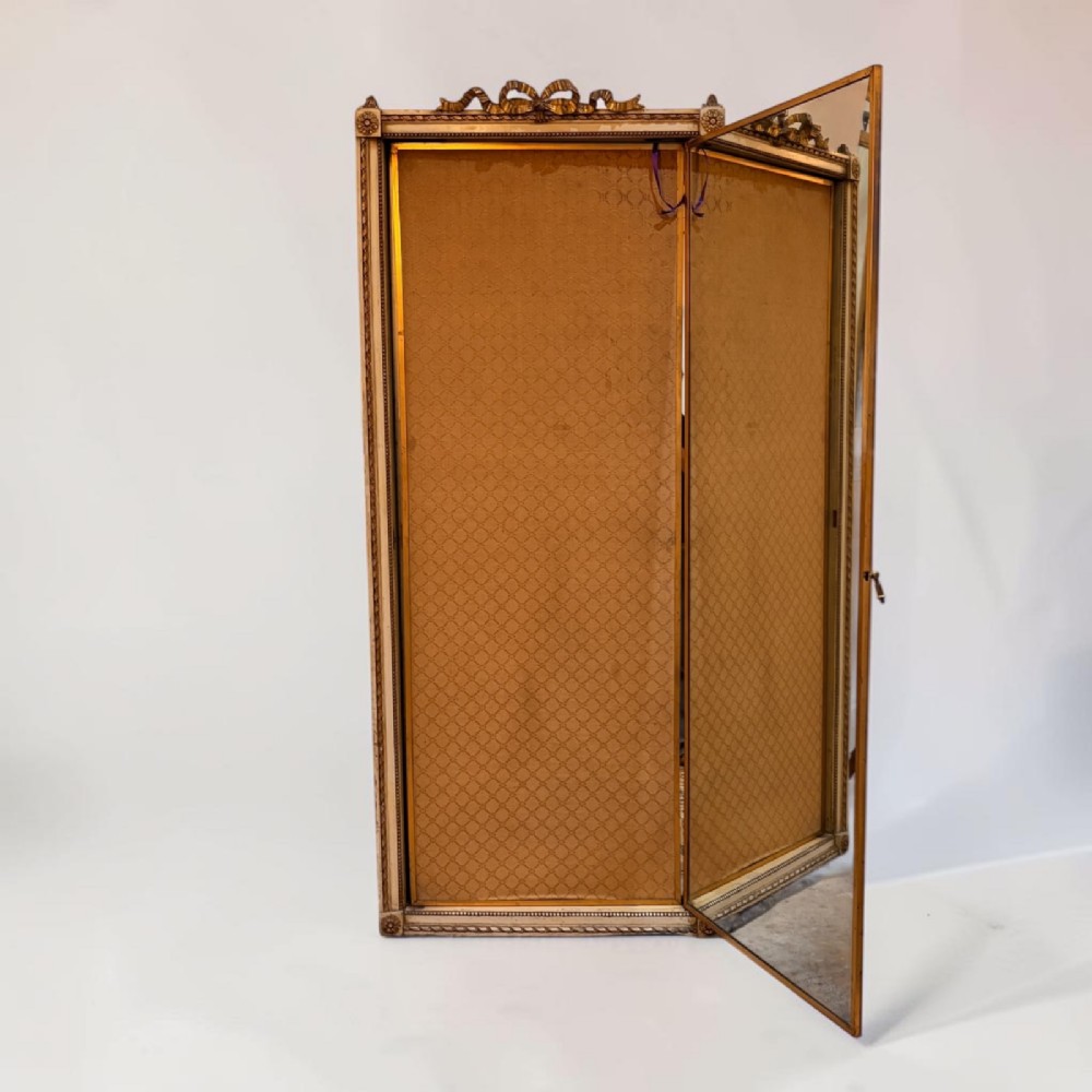 A large French giltwood triptych mirror featuring a ribbon-carved crest and three hinged folding mirror panels. View III