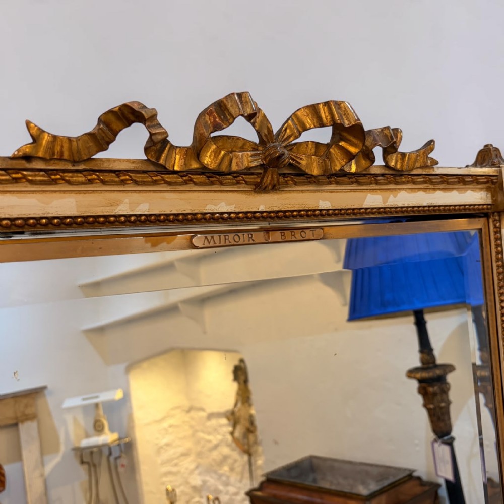 A large French giltwood triptych mirror featuring a ribbon-carved crest and three hinged folding mirror panels. View IV