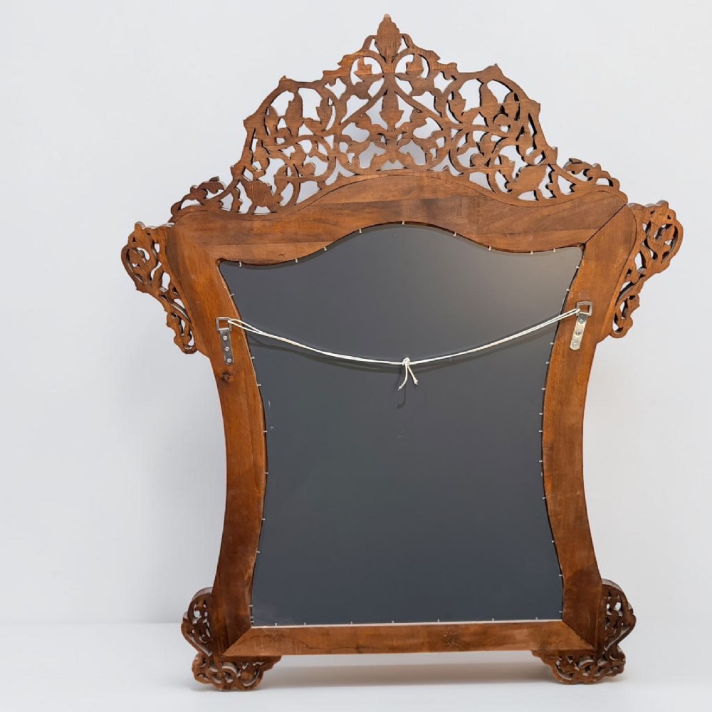 A Syrian wall mirror featuring a shaped dark wood frame with detailed mother-of-pearl floral inlays and an openwork pierced cresting. View V