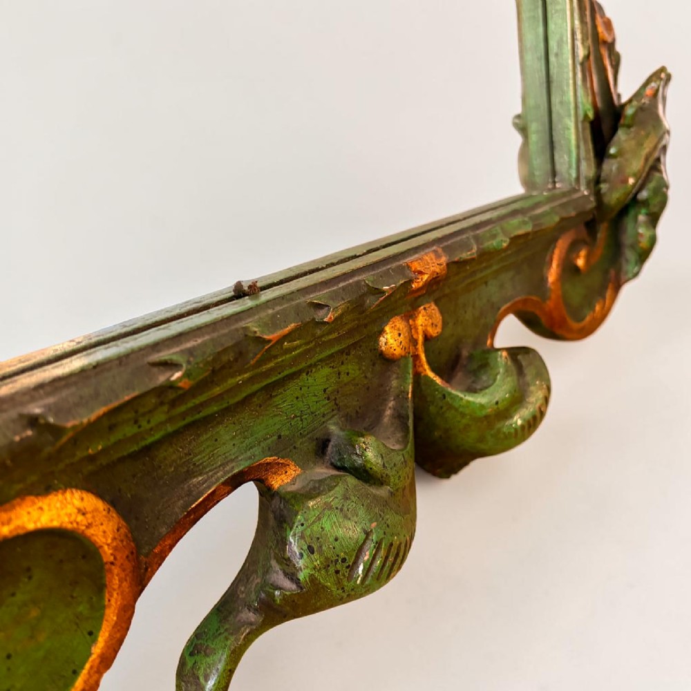 An ornate Italian Florentine style carved wooden mirror painted in olive green with gold leaf accents along scrolled acanthus leaf borders. View IV