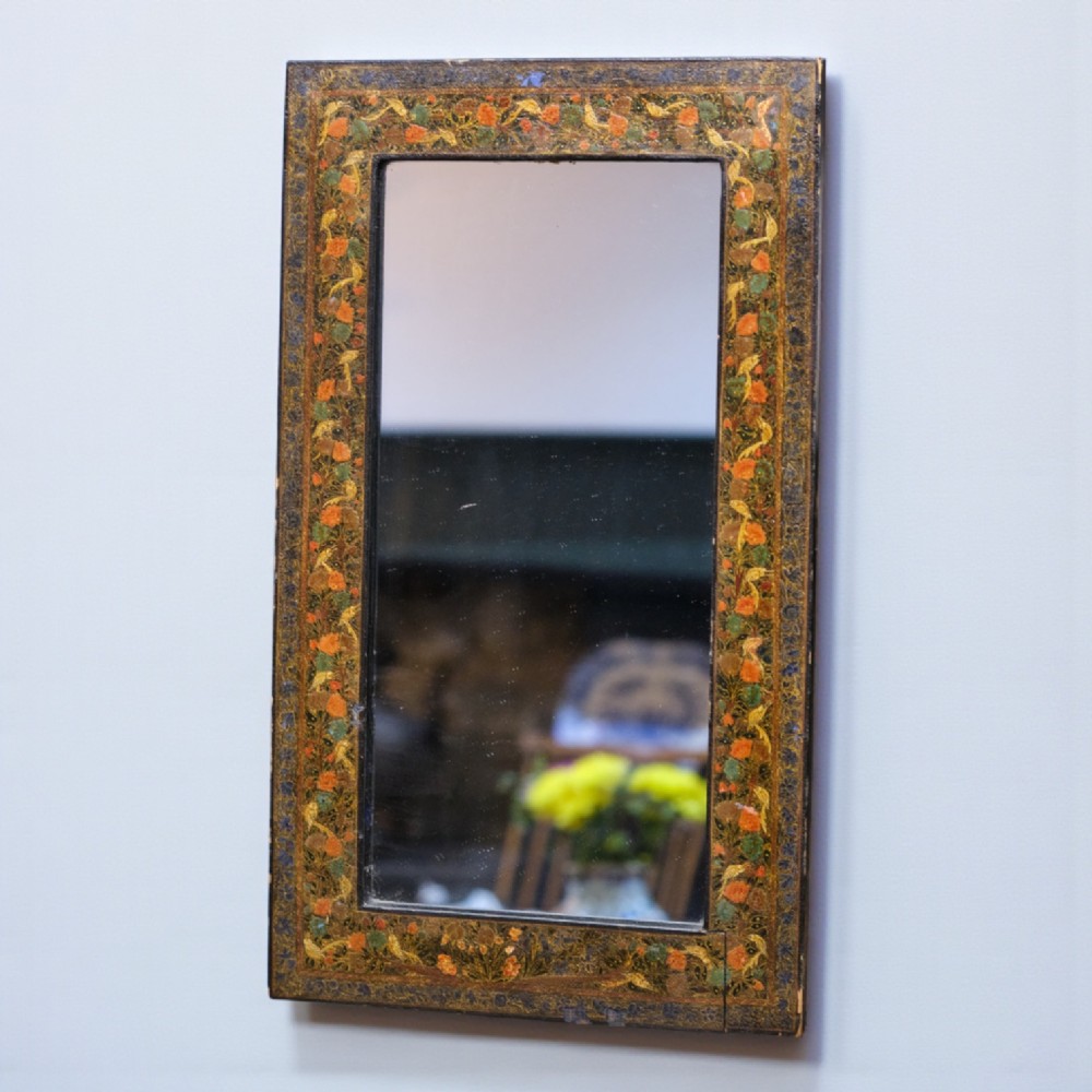 A rectangular wall mirror featuring a hand-painted lacquered frame decorated with intricate polychrome floral motifs in orange, green, and gold.