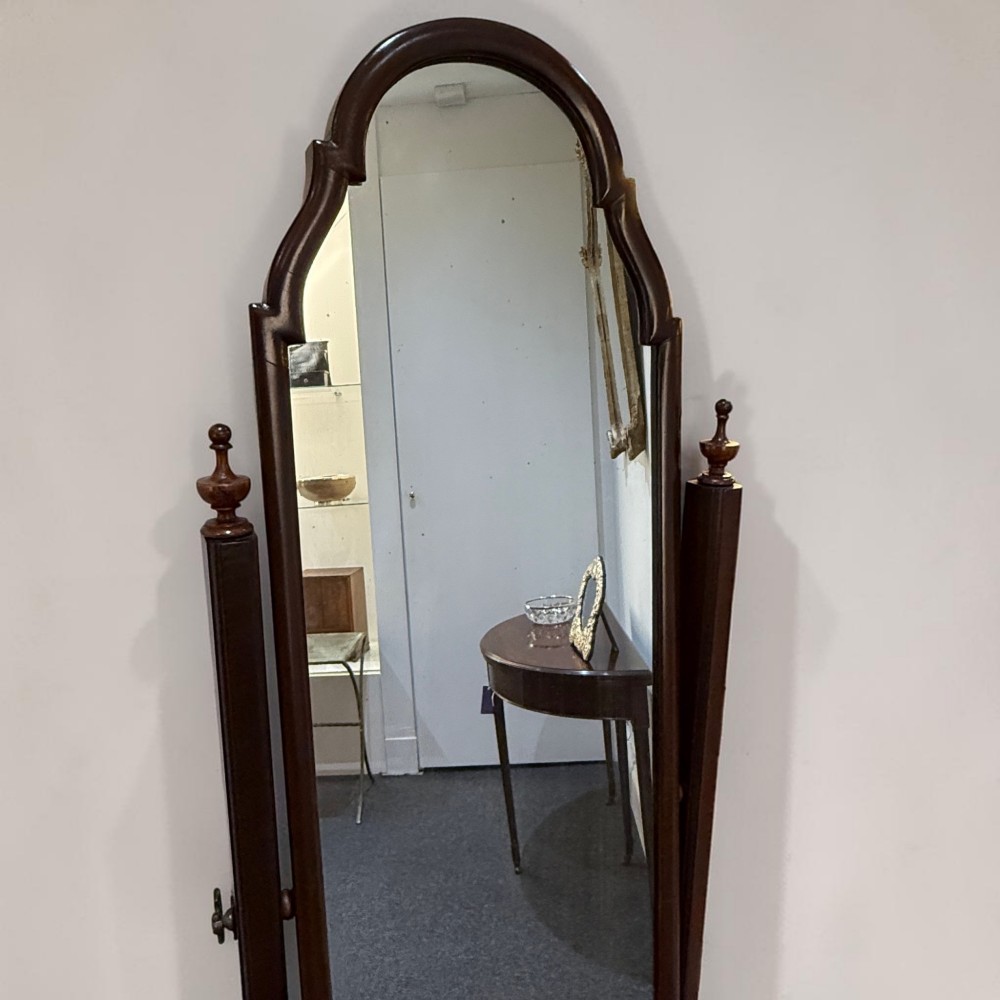 An Edwardian mahogany cheval dressing mirror featuring an arched top frame, turning brass pivots, and splayed sabre legs. View II