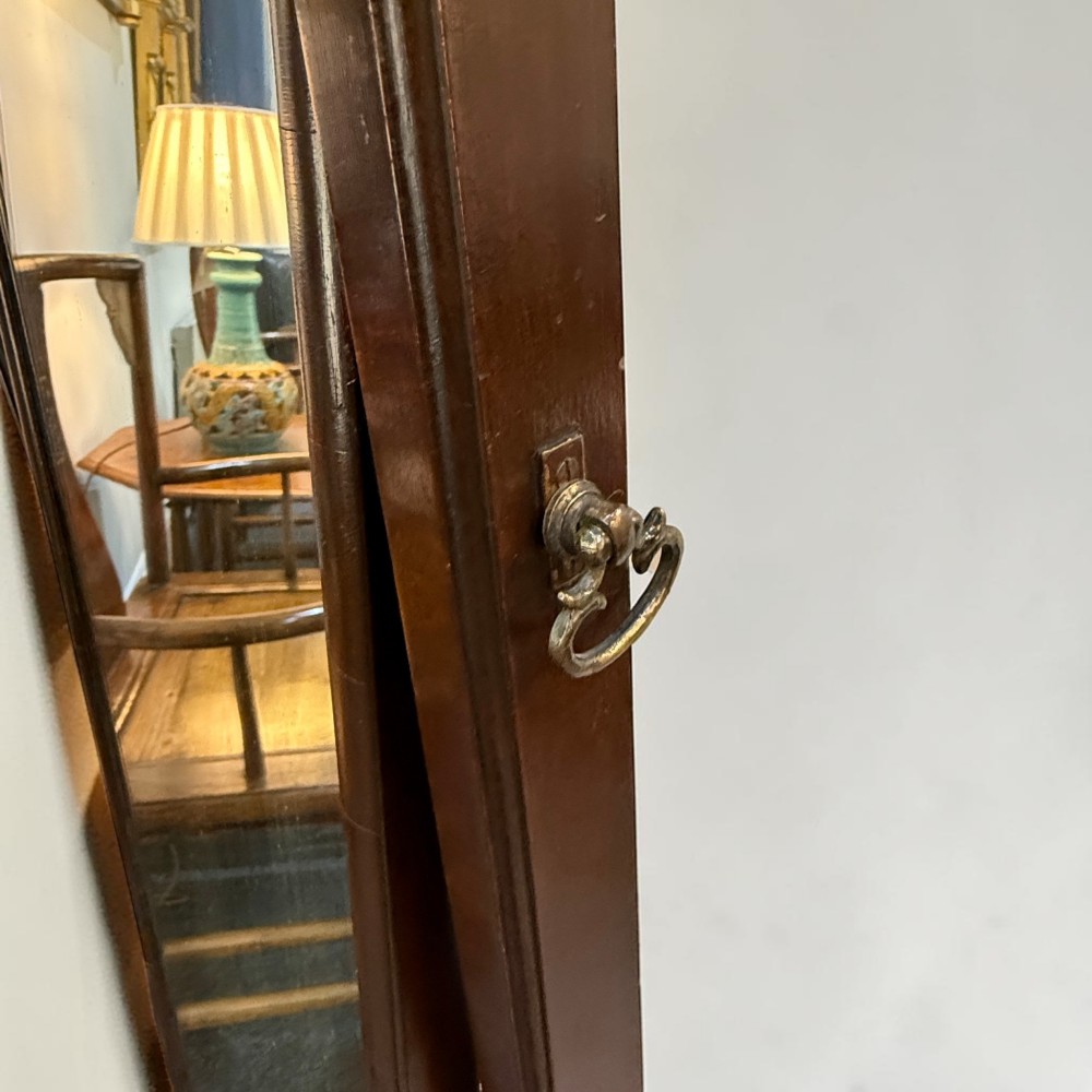 An Edwardian mahogany cheval dressing mirror featuring an arched top frame, turning brass pivots, and splayed sabre legs. View III
