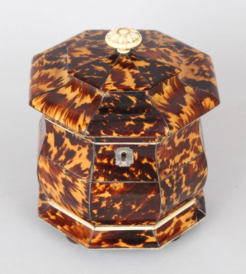 fig 1. An octagonal Regency period tea caddy decorated with mottled amber tortoiseshell veneer, a carved rosette finial, and a silver escutcheon.