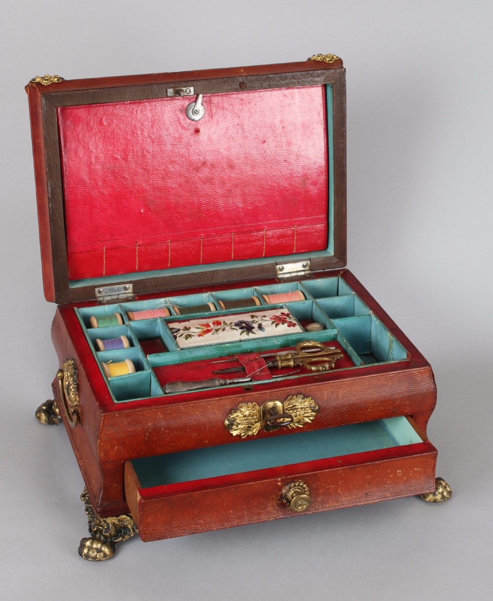 A Regency period sarcophagus-form work-box bound in red Russia leather with gilt-brass paw feet, side handles, and escutcheon. View II