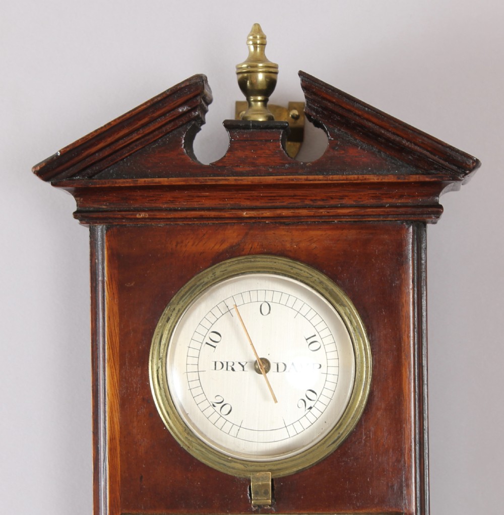 An early nineteenth-century mahogany stick barometer featuring a pedimented top, brass finial, silvered register plates, and a rounded cistern cover at the base. View II