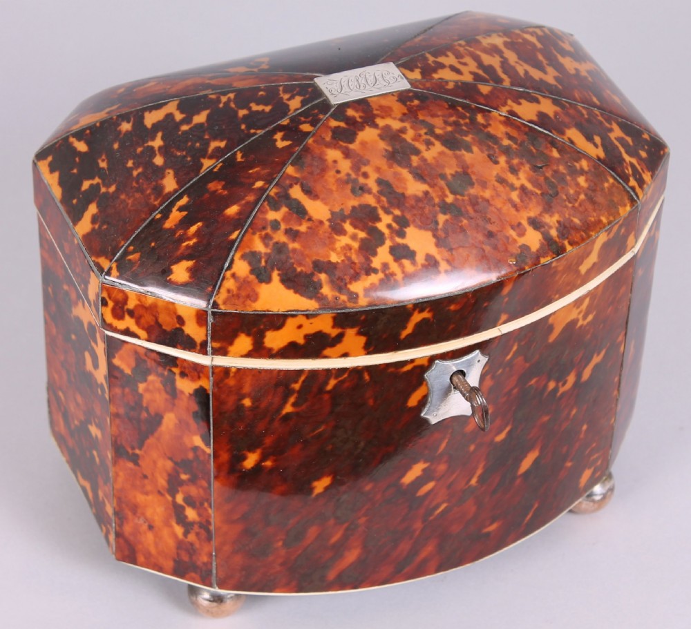 A Regency period bow-fronted tea caddy made from amber and brown tortoiseshell with a silver lid plate, escutcheon, and key.