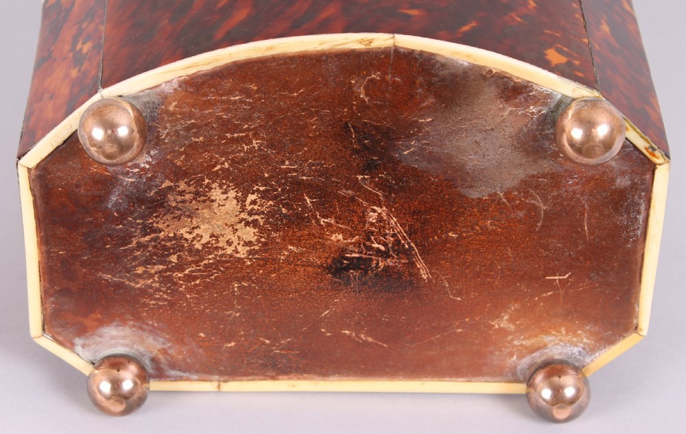 A Regency period bow-fronted tea caddy made from amber and brown tortoiseshell with a silver lid plate, escutcheon, and key. View IV