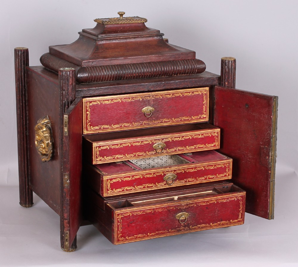An early nineteenth-century table-cabinet bound in deep red tooled leather, featuring fluted column corner posts, classical gilt-brass figure mounts on the twin doors, and dolphin side handles. View III