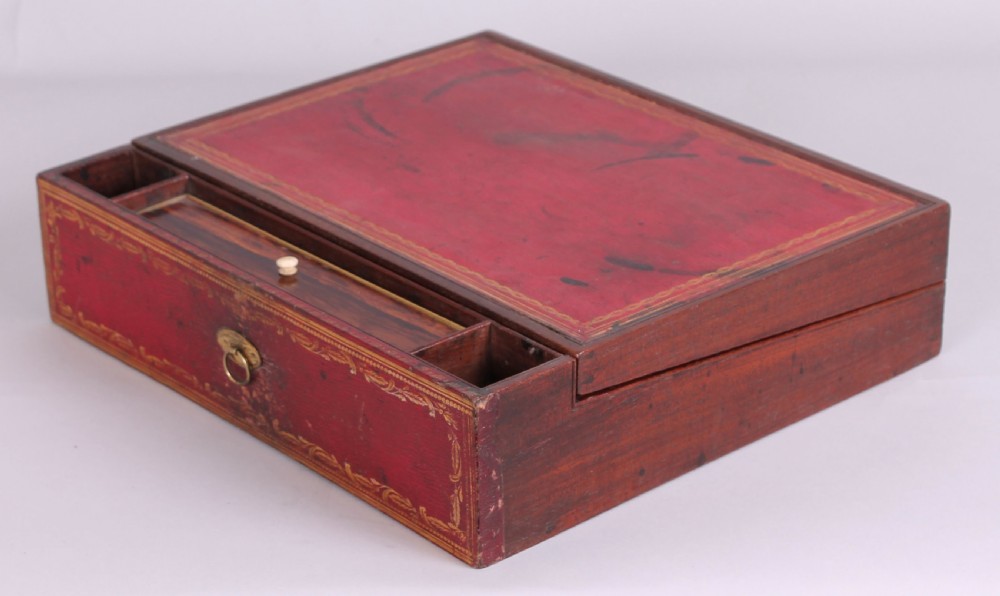 An early nineteenth-century table-cabinet bound in deep red tooled leather, featuring fluted column corner posts, classical gilt-brass figure mounts on the twin doors, and dolphin side handles. View V