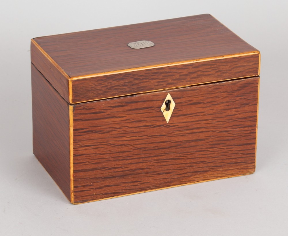 A rectangular George III partridge-wood tea caddy featuring dark dappled grain, boxwood stringing, a silver top plaque, and a diamond bone escutcheon.