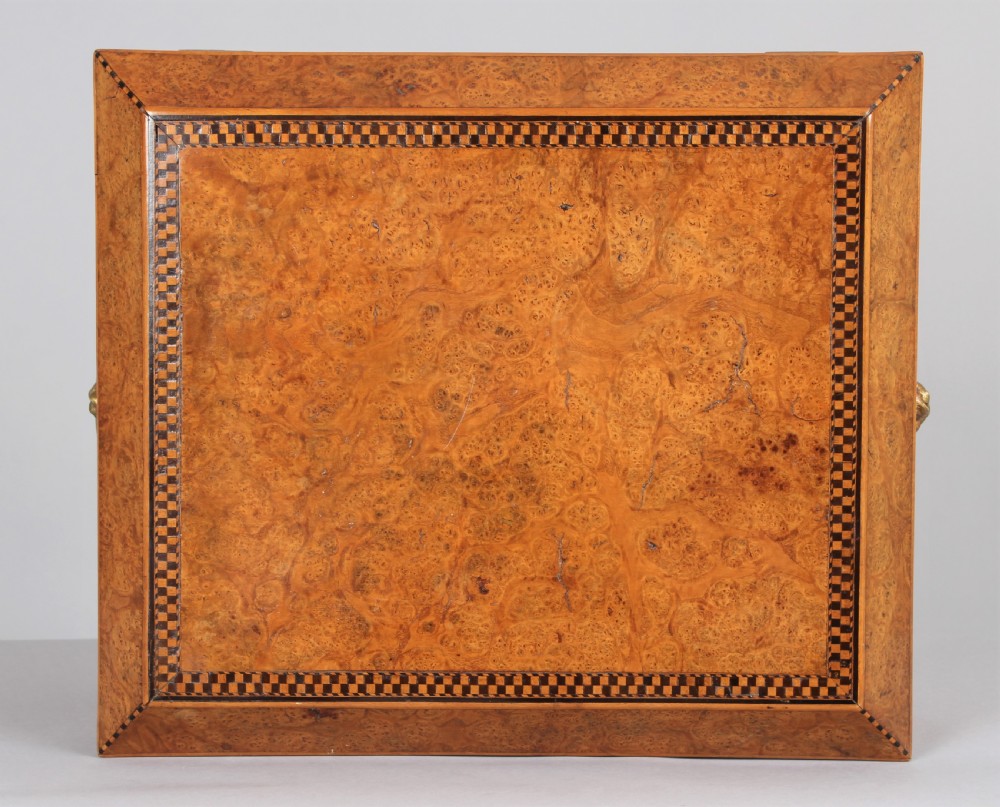 A Regency period sarcophagus-shaped work box crafted from golden birdseye maple with geometric ebony inlay, brass lion mask ring handles, and ball feet. View IV