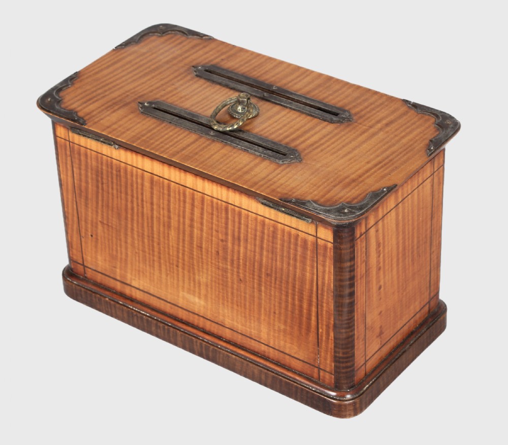 A rectangular 19th-century French wooden box with figured timber veneer, dual lid slots, central brass ring handle, metal corner mounts, and a key inserted in the front lock. View II