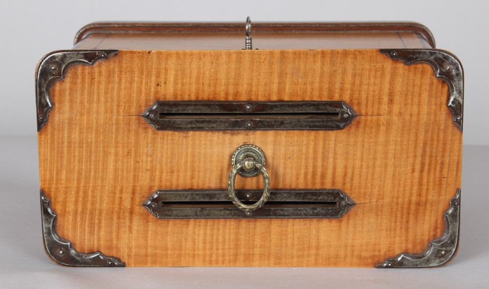 A rectangular 19th-century French wooden box with figured timber veneer, dual lid slots, central brass ring handle, metal corner mounts, and a key inserted in the front lock. View III