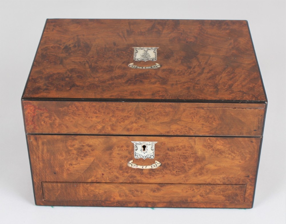 A rectangular Victorian burr walnut dressing box featuring a lockable lid, silver escutcheon, and inlaid top cartouche against a plain background. View II