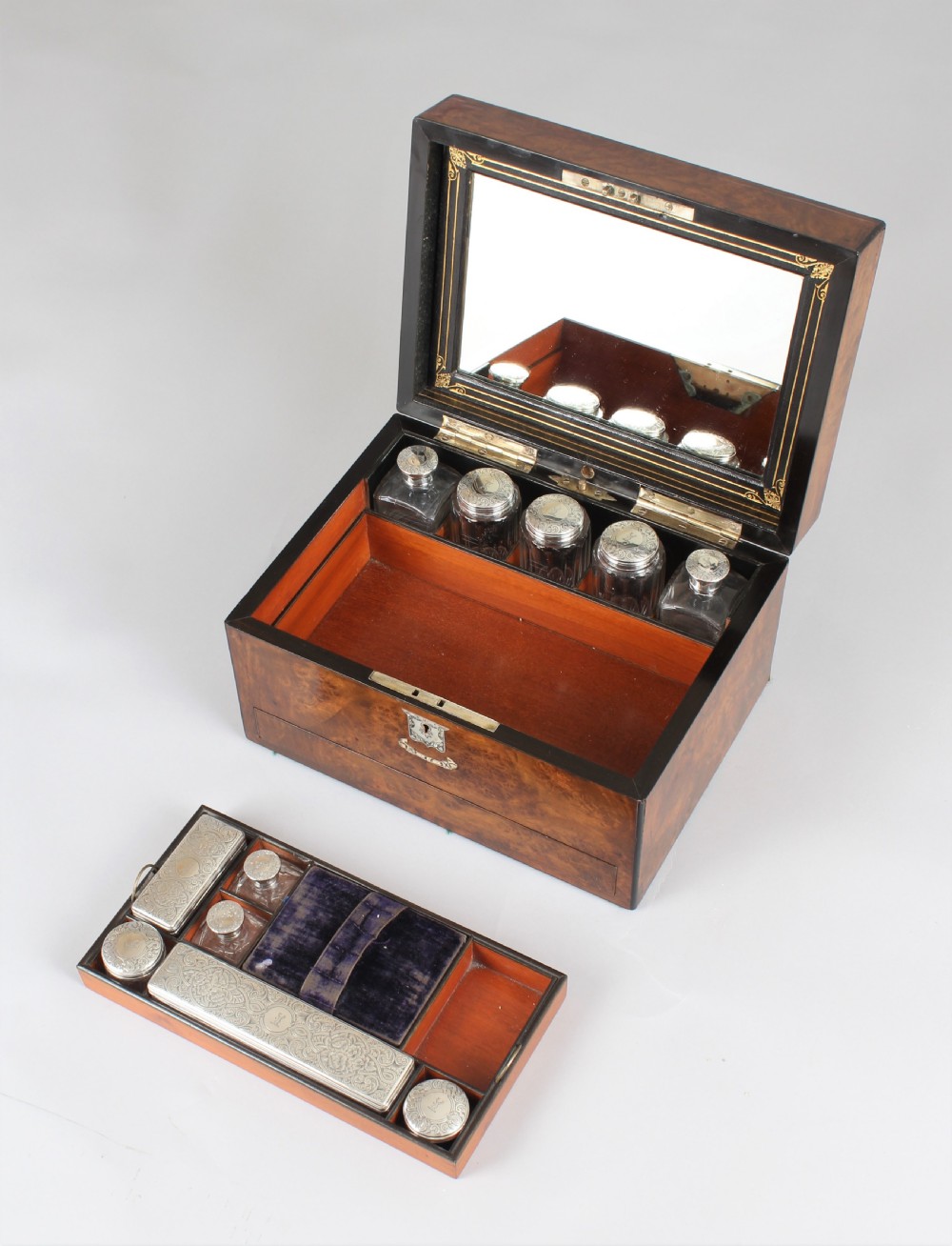 A rectangular Victorian burr walnut dressing box featuring a lockable lid, silver escutcheon, and inlaid top cartouche against a plain background. View VI