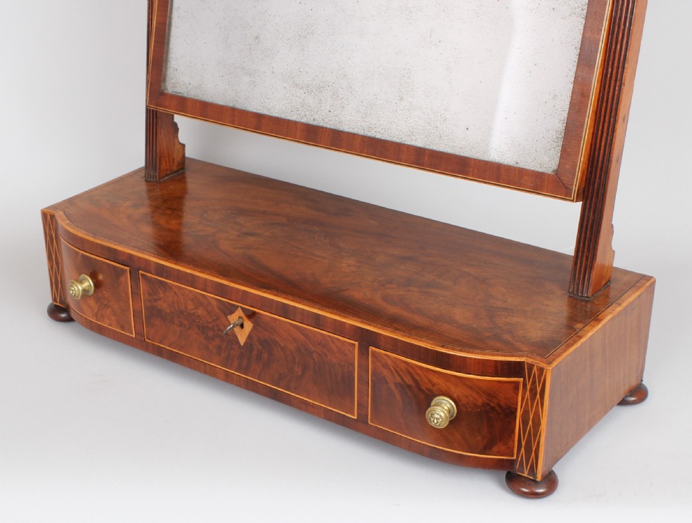 A George IV mahogany toilet mirror featuring an adjustable rectangular glass plate supported by fluted uprights over a bow-fronted drawer base. View III