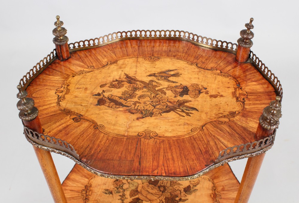 A mid-19th century French style wooden etagere featuring three serpentine tiers decorated with floral marquetry inlay, a pierced brass gallery rail, and top urn finials. View IV