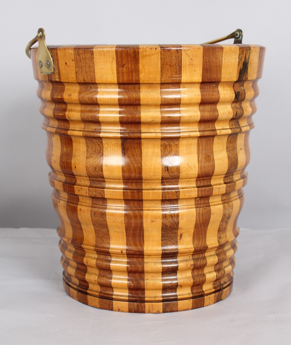 An early nineteenth-century Dutch teestoof bucket featuring alternating light and dark wooden staves, ribbed horizontal shaping, and a brass swing handle. View III