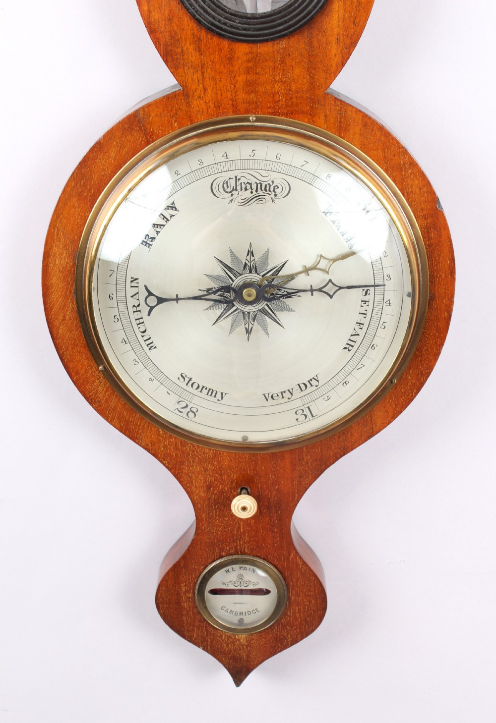 A Victorian mahogany wheel barometer featuring an onion top, upper hygrometer dial, enclosed glass thermometer, central convex mirror, silvered main dial, and lower spirit level plate by W.E. Pain of Cambridge. View II