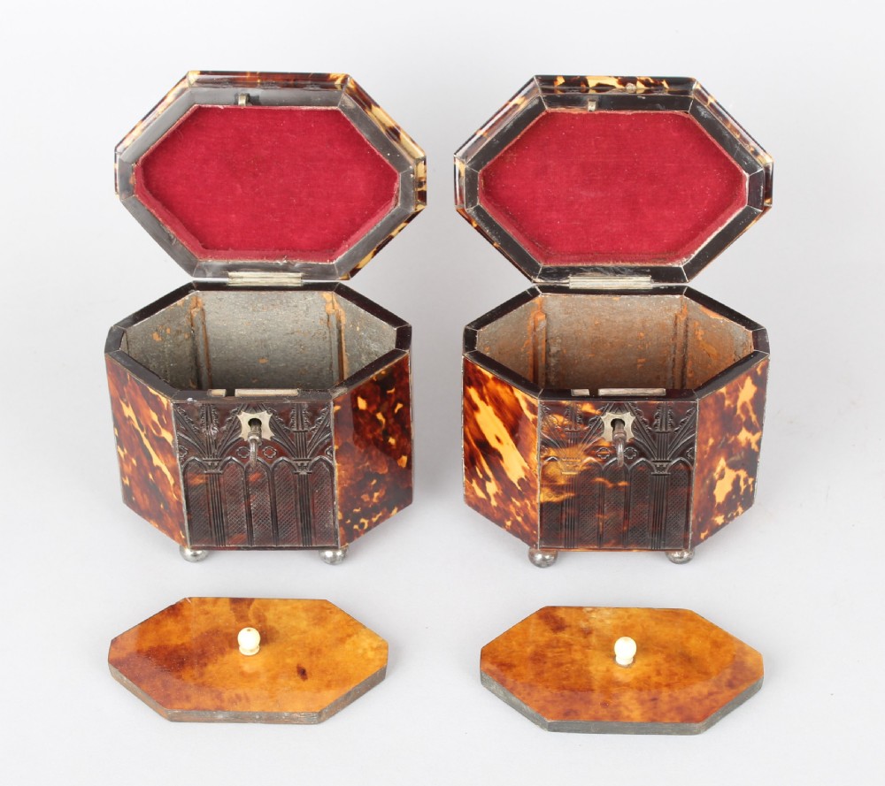 A pair of octagonal George IV period miniature tea caddies crafted with mottled tortoiseshell veneer, silver urn finials, ball feet, and gothic arcading. View IV