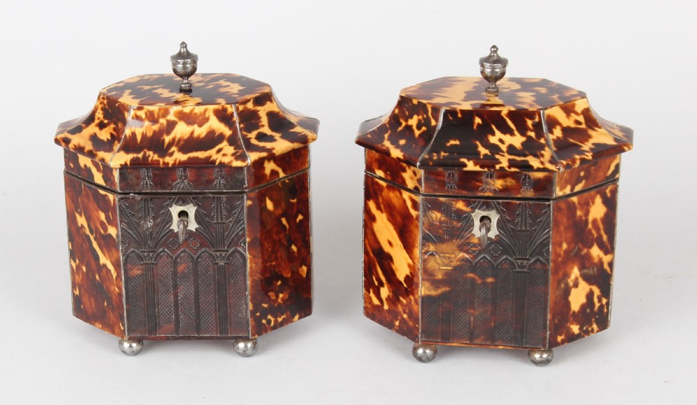 A pair of octagonal George IV period miniature tea caddies crafted with mottled tortoiseshell veneer, silver urn finials, ball feet, and gothic arcading. View V
