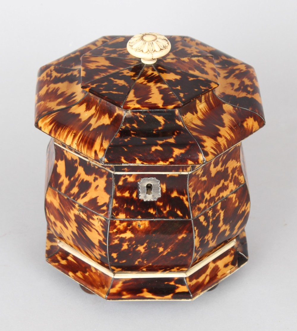 An octagonal Regency period tea caddy decorated with mottled amber tortoiseshell veneer, a carved rosette finial, and a silver escutcheon. View II