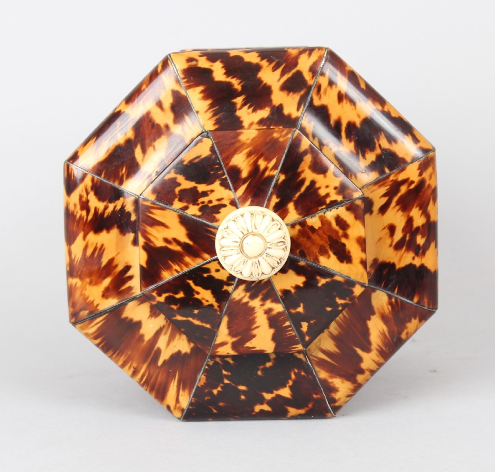 An octagonal Regency period tea caddy decorated with mottled amber tortoiseshell veneer, a carved rosette finial, and a silver escutcheon. View III