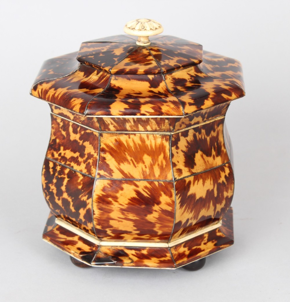 An octagonal Regency period tea caddy decorated with mottled amber tortoiseshell veneer, a carved rosette finial, and a silver escutcheon. View IV