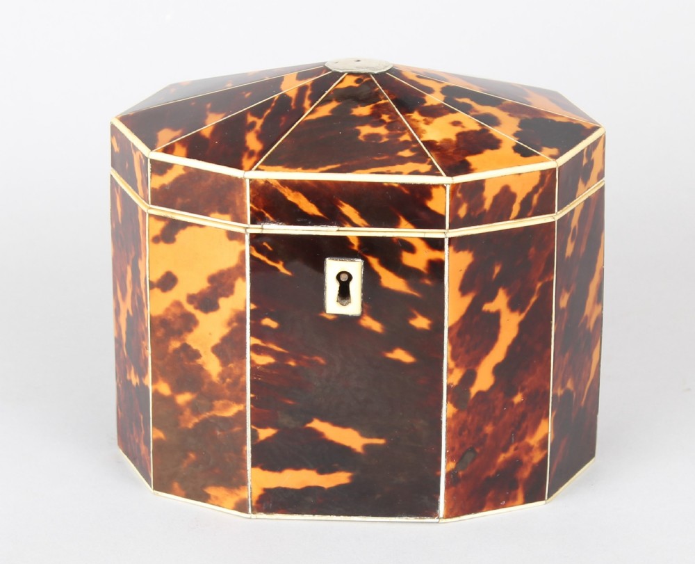 A George III period decagonal tea caddy covered in mottled amber and dark brown tortoiseshell veneer with bone stringing and a small escutcheon.