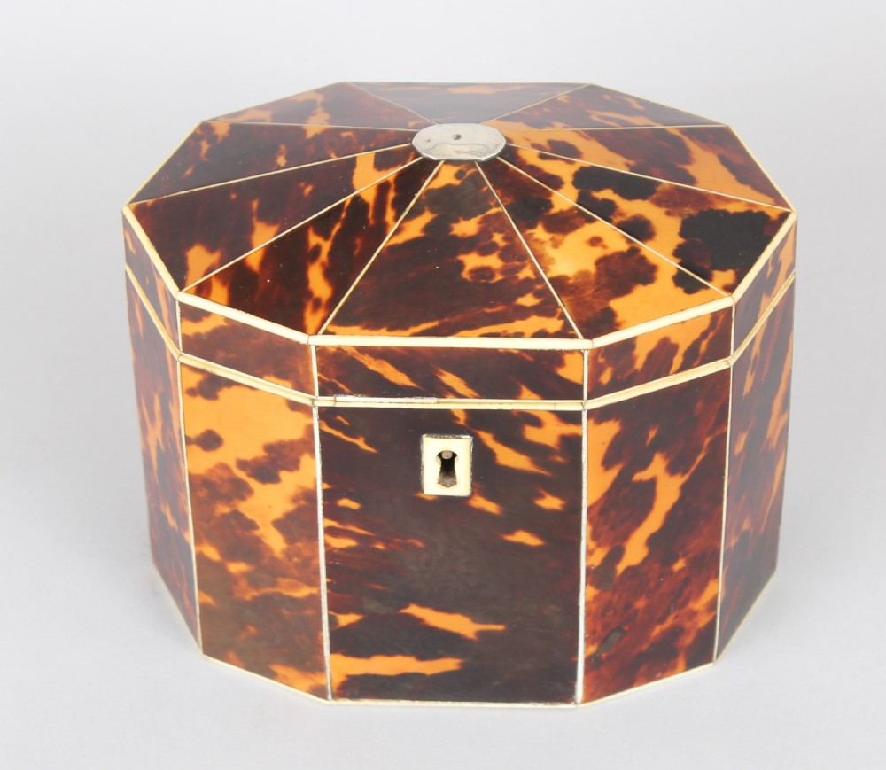 A George III period decagonal tea caddy covered in mottled amber and dark brown tortoiseshell veneer with bone stringing and a small escutcheon. View II