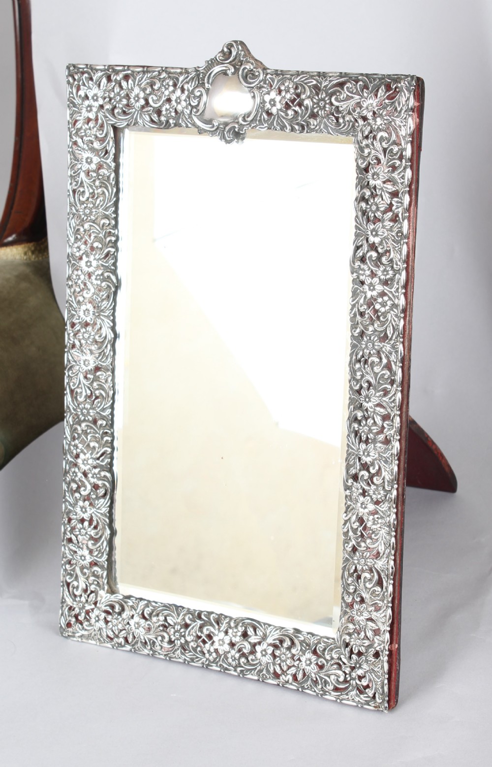 A rectangular Victorian sterling silver easel table mirror with pierced floral scrollwork and a blank crest cartouche.