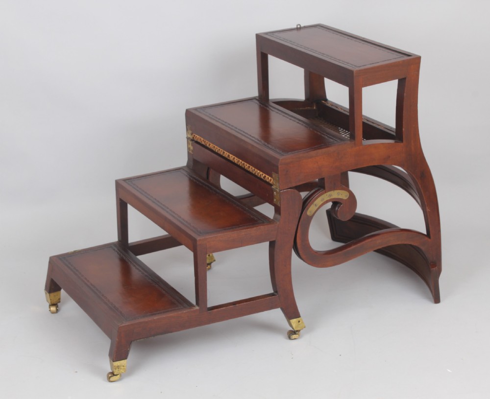 A Regency period mahogany metamorphic library chair with scroll armrests, a buttoned leather seat, and brass castors. View III