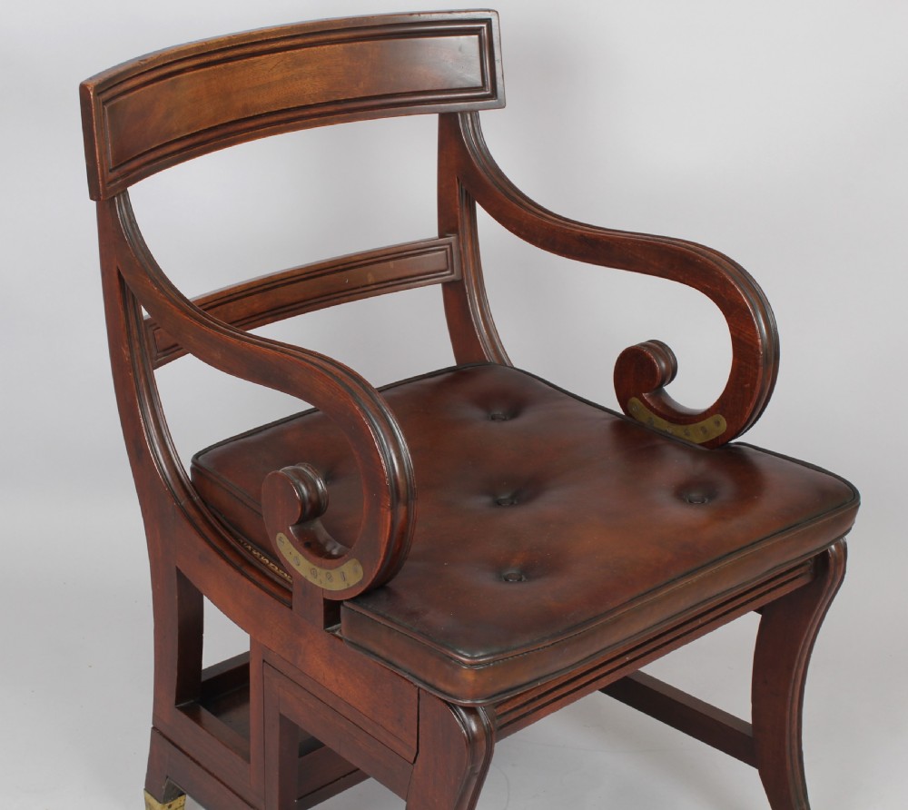 A Regency period mahogany metamorphic library chair with scroll armrests, a buttoned leather seat, and brass castors. View V