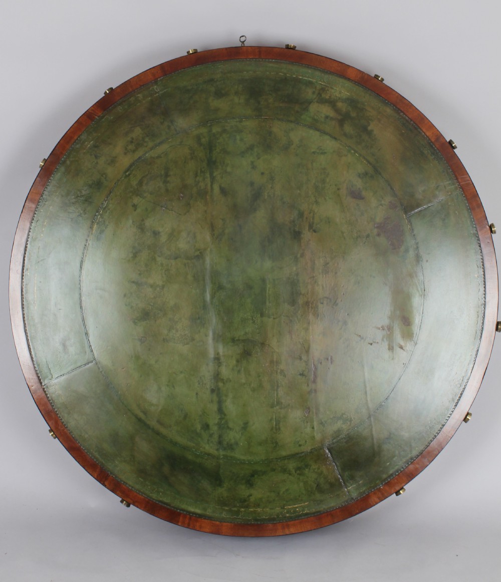 A Regency mahogany drum table featuring a green leather inset top, frieze drawers with brass handles, and a turned pedestal with four splayed reeded legs on brass castors. View III