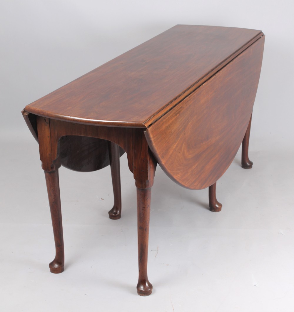 An 18th-century oval mahogany drop-leaf dining table supported by slender cabriole legs ending in pad feet. View II