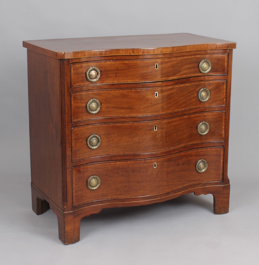 A late eighteenth-century mahogany serpentine chest of drawers featuring four graduated drawers with brass handles resting on bracket feet. View II