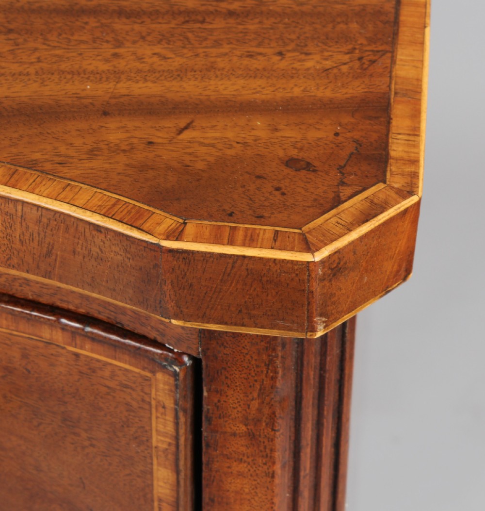 A late eighteenth-century mahogany serpentine chest of drawers featuring four graduated drawers with brass handles resting on bracket feet. View V