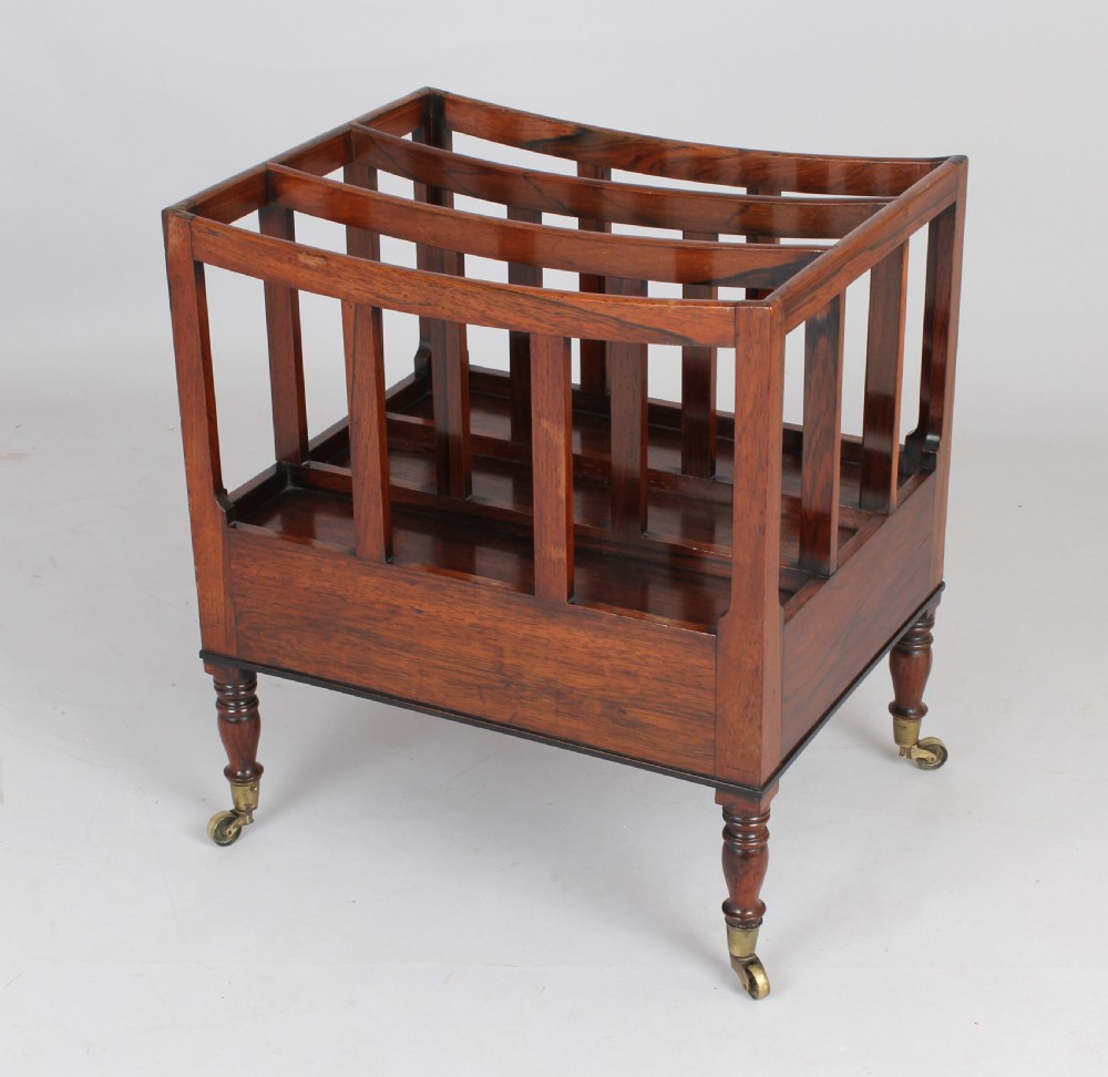 An antique George IV rosewood canterbury featuring three upper divisions, slatted side panels, a lower drawer with brass knobs, and turned legs with brass castors. View IV