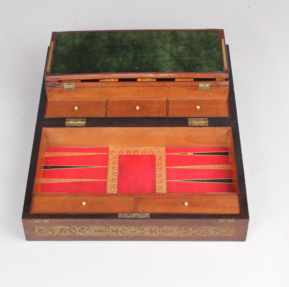 An open early Victorian rosewood games compendium featuring small wooden drawers, a green velvet playing surface, and a red gilt-tooled backgammon interior section. View XIV